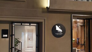 A hotel entrance with a metal gate, a sign reading "LASTARRIA Hotel & Spa", and a number "285" on the wall. - Lastarria Hotel (Santiago)