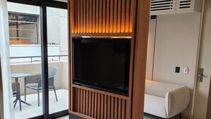A modern living room with a built-in TV, a sofa, and a dining area. - Lastarria Hotel (Santiago)