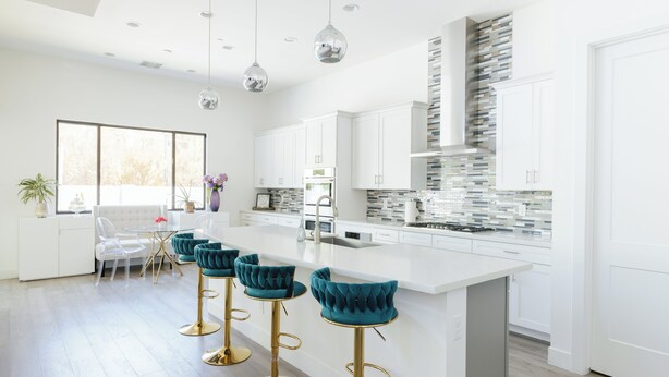 Una cocina moderna con armarios blancos, una isla grande y taburetes de bar.