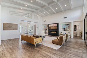 A spacious living area with a fireplace, leather sofas, and a large TV screen.