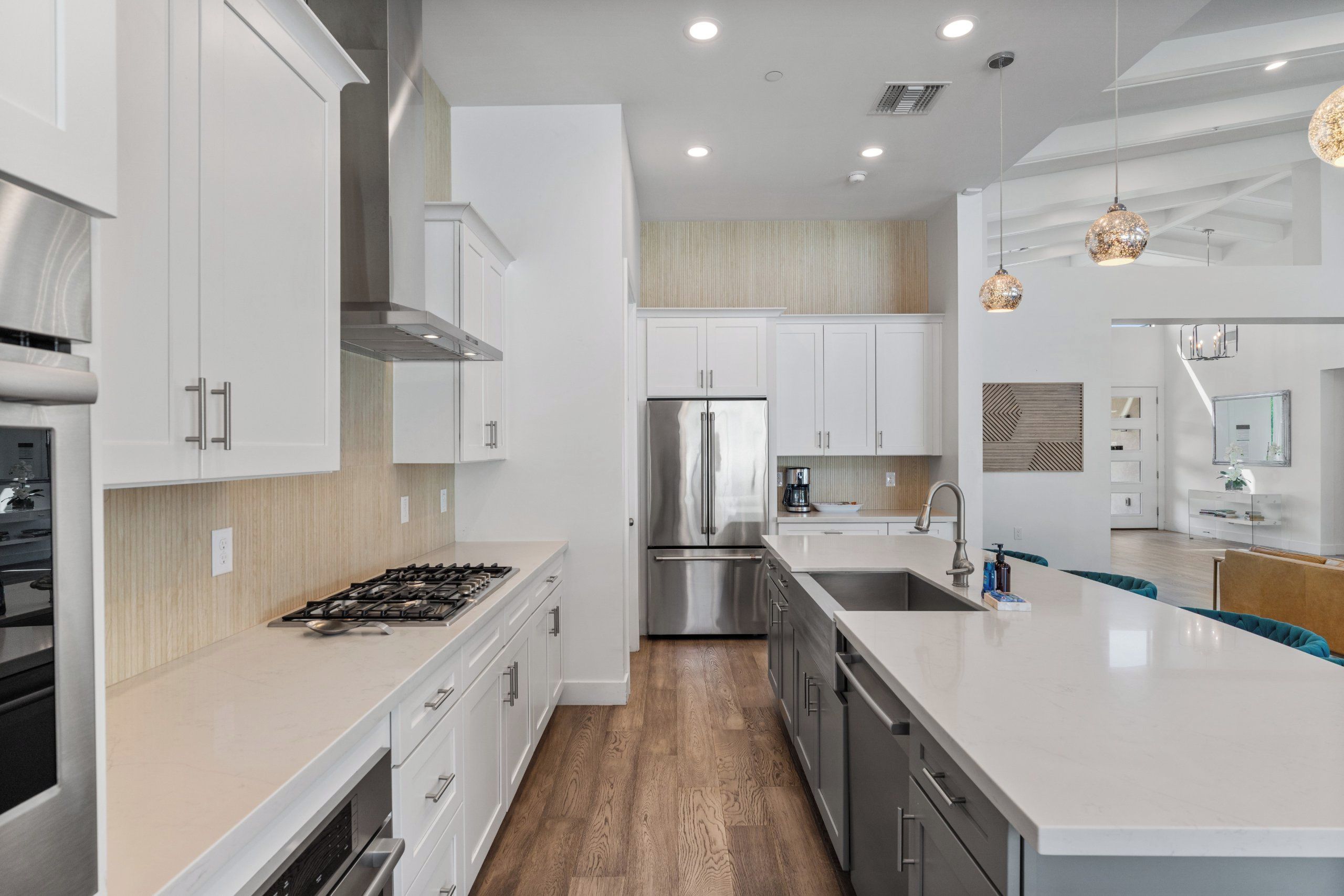 A modern kitchen with white cabinetry, stainless steel appliances, and a central island with seating.
