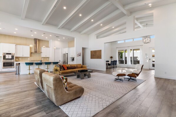 A spacious living area with a large sofa, a coffee table, and a dining area with chairs.