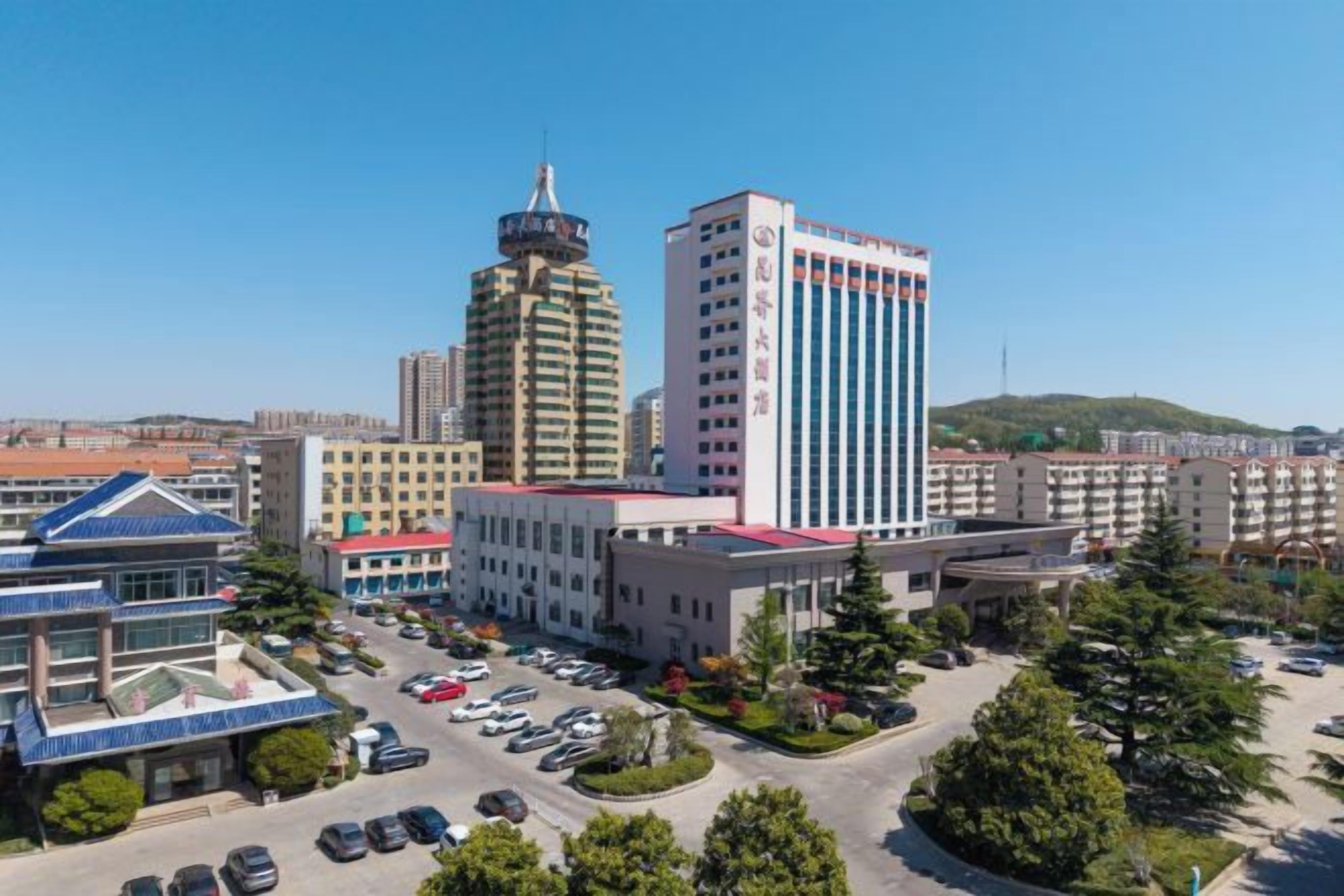 A multi-story hotel with a parking lot and a central building with a red roof.
