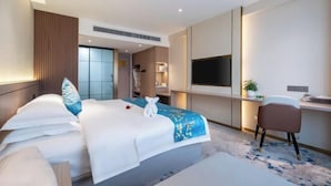 A hotel room with a bed, a desk, a chair, and a TV. - Kunyu Hotel (Weihai)