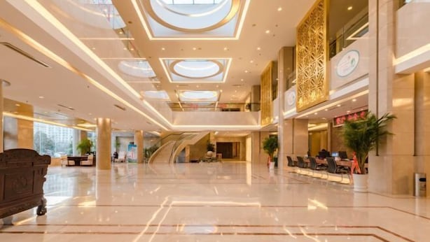 A spacious lobby with a high ceiling, a central staircase, and a seating area. - Kunyu Hotel (Weihai)
