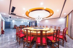 Un salón de conferencias con una mesa redonda, sillas rojas y una araña de cristal.