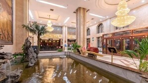 Un hall con una fuente central, una recepción y una escalera que conduce a los pisos superiores.