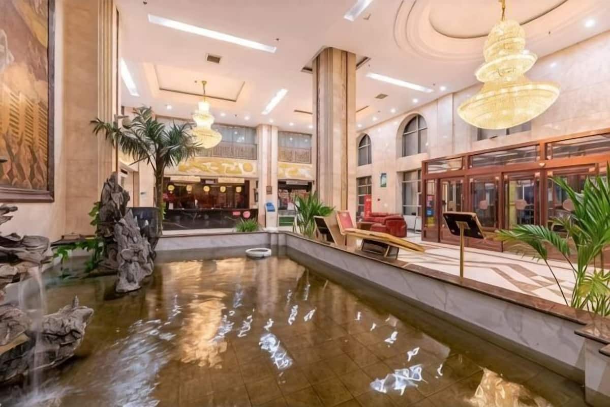 A lobby with a central water feature, a reception desk, and a staircase leading to upper floors.