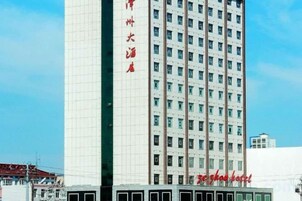 Un edificio alto con múltiples ventanas y un letrero con caracteres rojos.