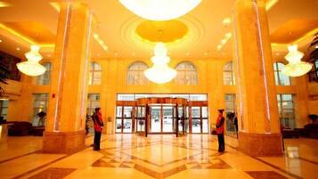 A spacious lobby with a grand chandelier, large columns, and a revolving door.