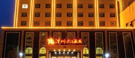 A multi-story hotel with a prominent entrance and illuminated signage.