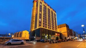 Un edificio de hotel alto con señalización iluminada y una entrada bien iluminada.