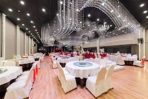 A banquet hall with round tables, white chairs, and a ceiling adorned with hanging lights. - Zezhou Hotel (Pingquan)