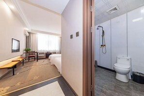 Hotellihuone, jossa on sänky, yöpöytä, tuoli ja pieni työpöytä, jonka päällä on kasvi.