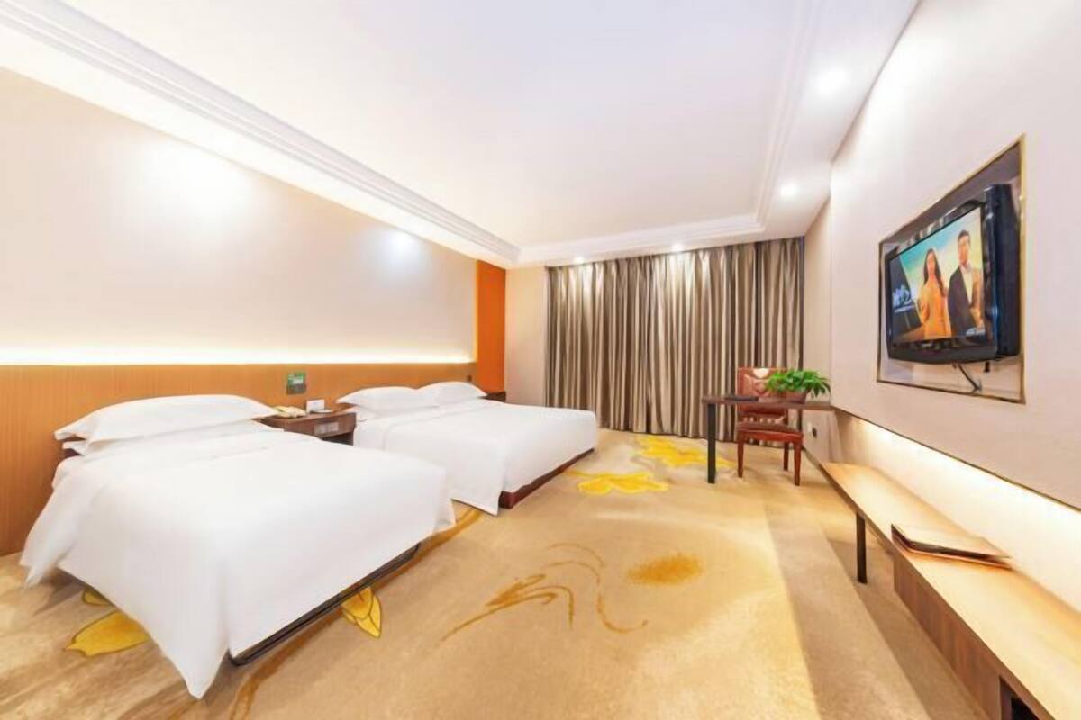 A hotel room with two beds, a desk, a chair, a TV, and a curtain.