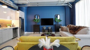 A modern living room with a blue accent wall, a flat-screen TV, a sofa, and a yellow armchair.