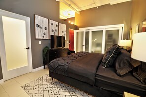 A bedroom with a bed, a dresser, a mirror, and a wardrobe.