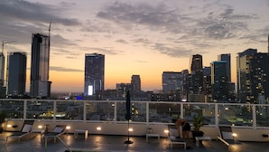 A rooftop terrace with lounge chairs, a small table, and potted plants. - Live Like a Legend In DTLA + 360° Pool + Parking (Los Angeles)
