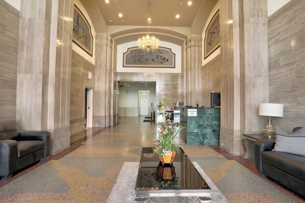 A spacious lobby with a reception desk, seating area, and a chandelier.