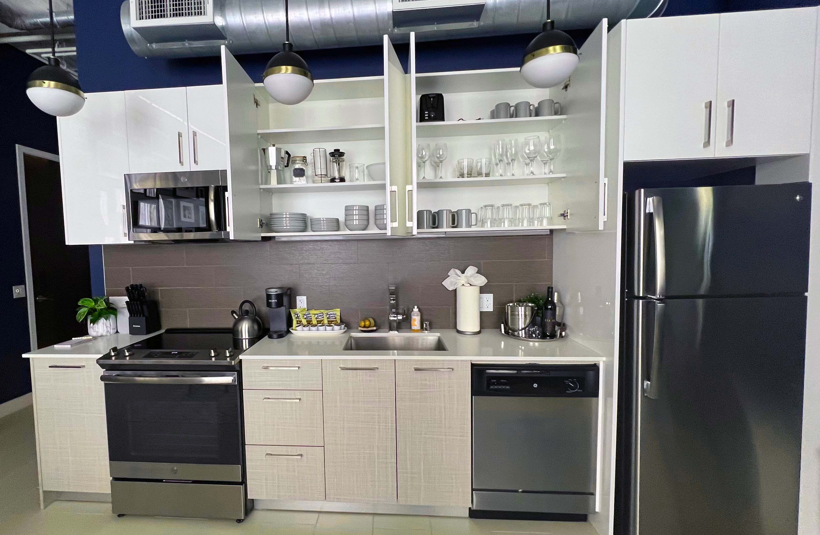 A modern kitchen with stainless steel appliances, white cabinetry, and pendant lighting.