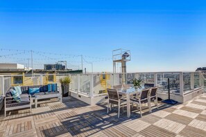 A rooftop terrace with a wooden deck, outdoor seating, and a clear view of the city skyline.