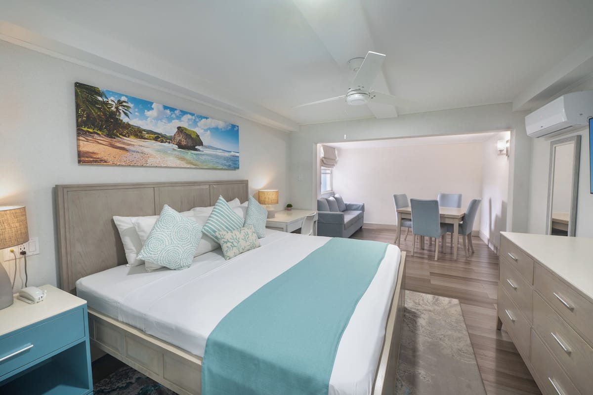 Habitación de hotel con cama, mesitas de noche, escritorio, silla, zona de comedor y aire acondicionado.