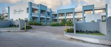 A modern multi-story hotel with a prominent "Blue Haven" sign, featuring balconies and a landscaped entrance.