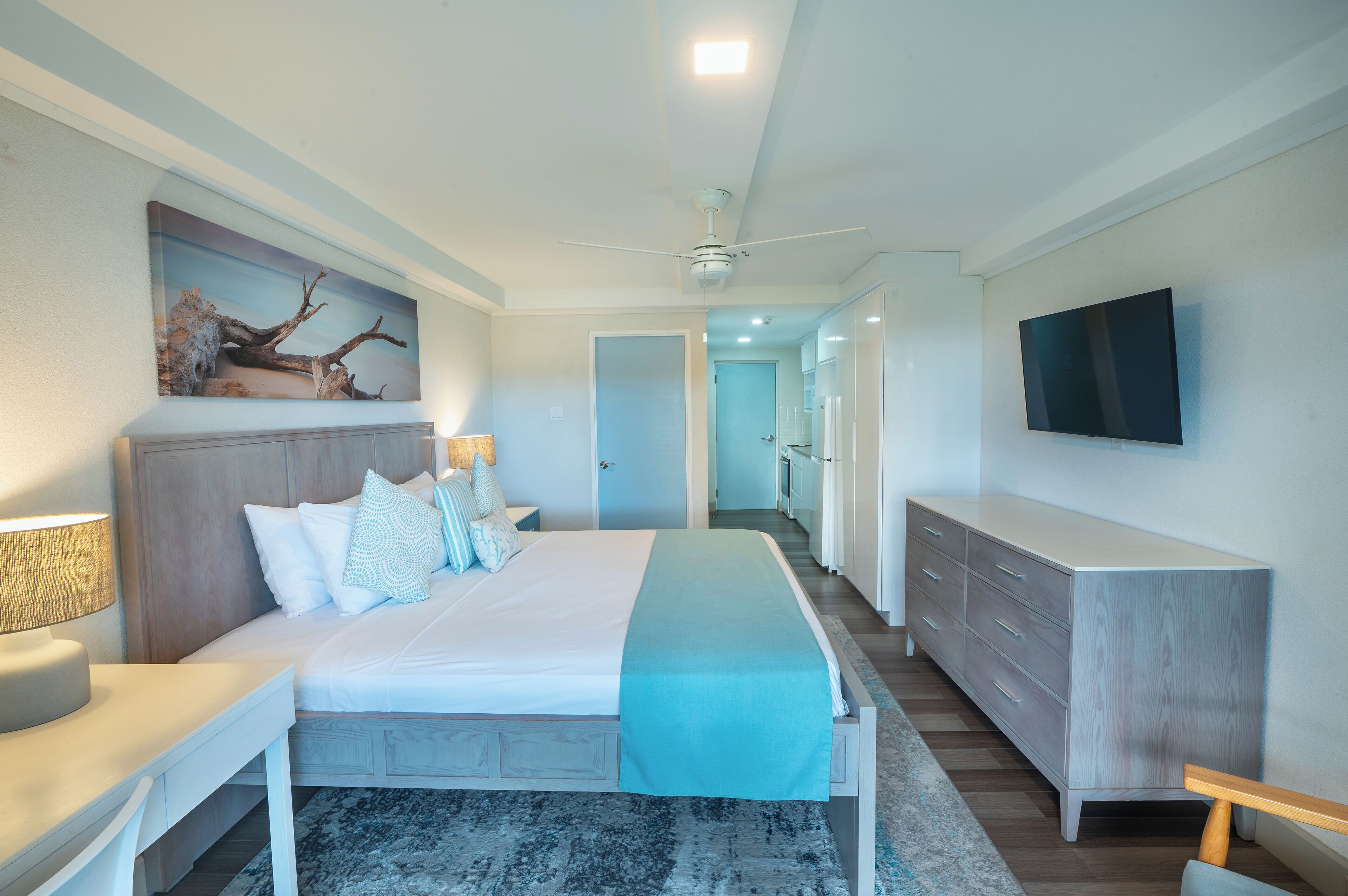Une chambre d’hôtel moderne dotée d’un grand lit, d’une télévision à écran plat, d’un bureau et d’une armoire.