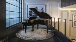 Ein prächtiges Klavier in einem geräumigen, elegant eingerichteten Zimmer mit einem großen Fenster, einem gemusterten Teppich und einem gerahmten Kunstwerk an der Wand.