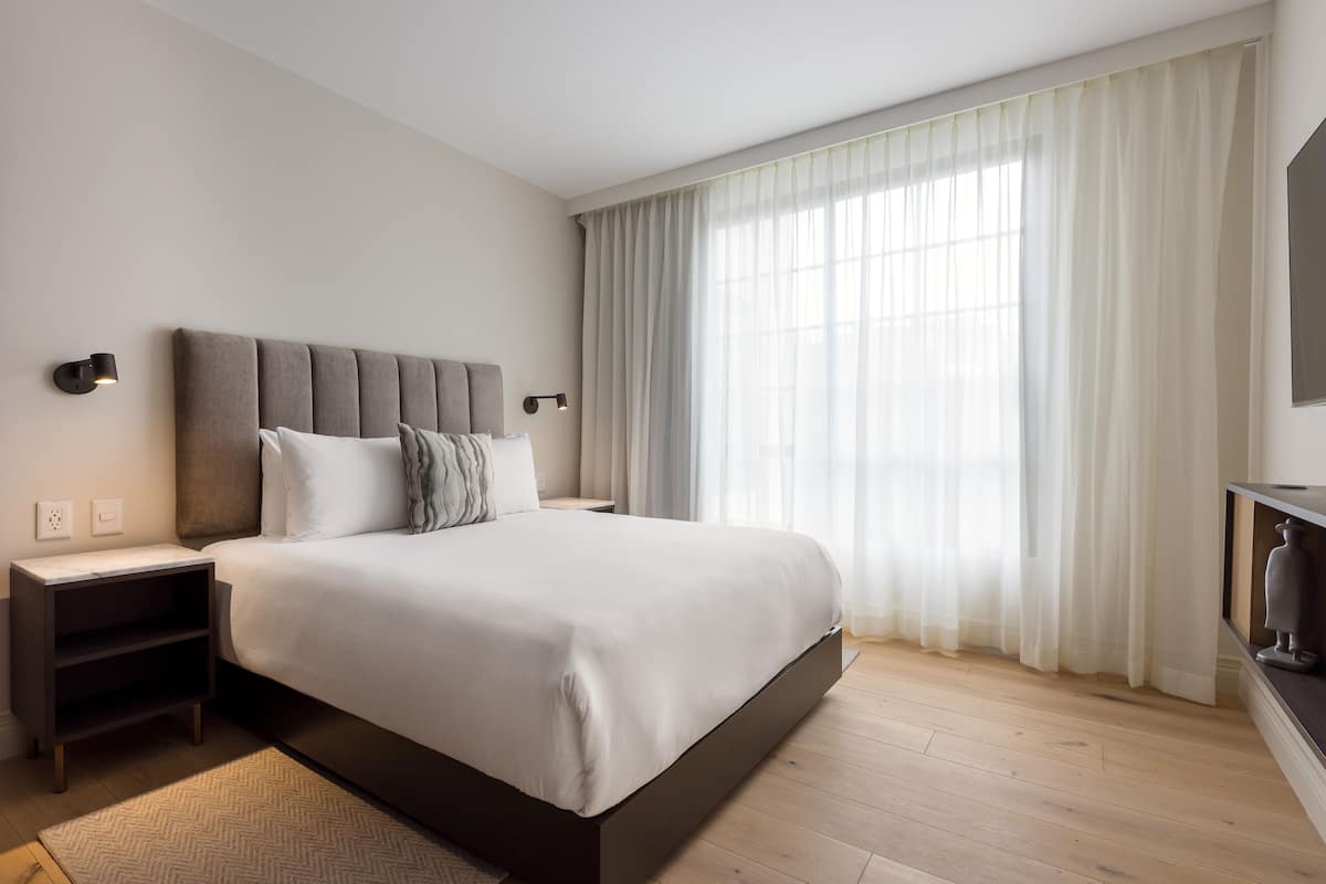 Ein modernes Schlafzimmer mit einem großen Bett, einem Nachttisch und einer Wandlampe.