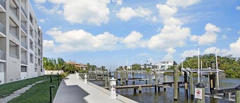A waterfront walkway with a modern building on one side and a marina with docks.