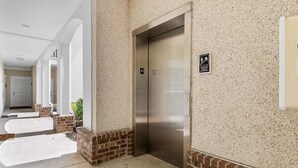 An elevator in a building with a speckled wall and a sign indicating it is the first floor.