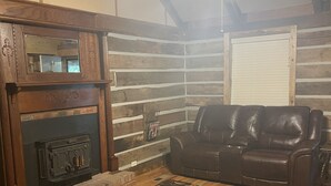 A cozy living room with a fireplace, leather sofa, and a patterned rug.