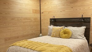 A wooden-paneled room with a bed, a ceiling fan, and a nightstand.