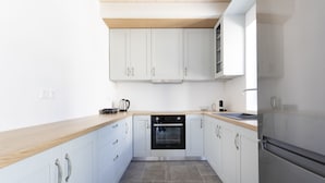 A modern kitchen with white cabinets, a stainless steel oven, and a wooden countertop. - Raise Spetses Villa Yasemi (Spetses)