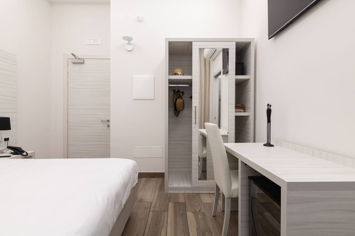 Una habitación de hotel moderna con cama, escritorio y armario.