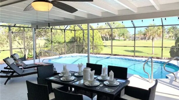 A covered outdoor area with a pool, dining table set for four, and lounge chairs. - Heated Pool House On Golf Course/7 min from Beach - Discounted (Rotonda West)
