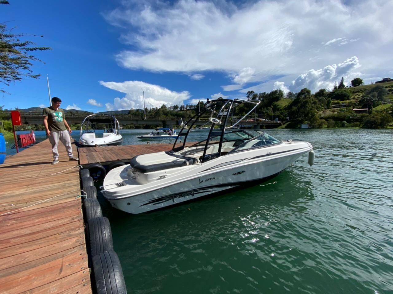 Un bote amarrado en un muelle de madera con una persona cerca.