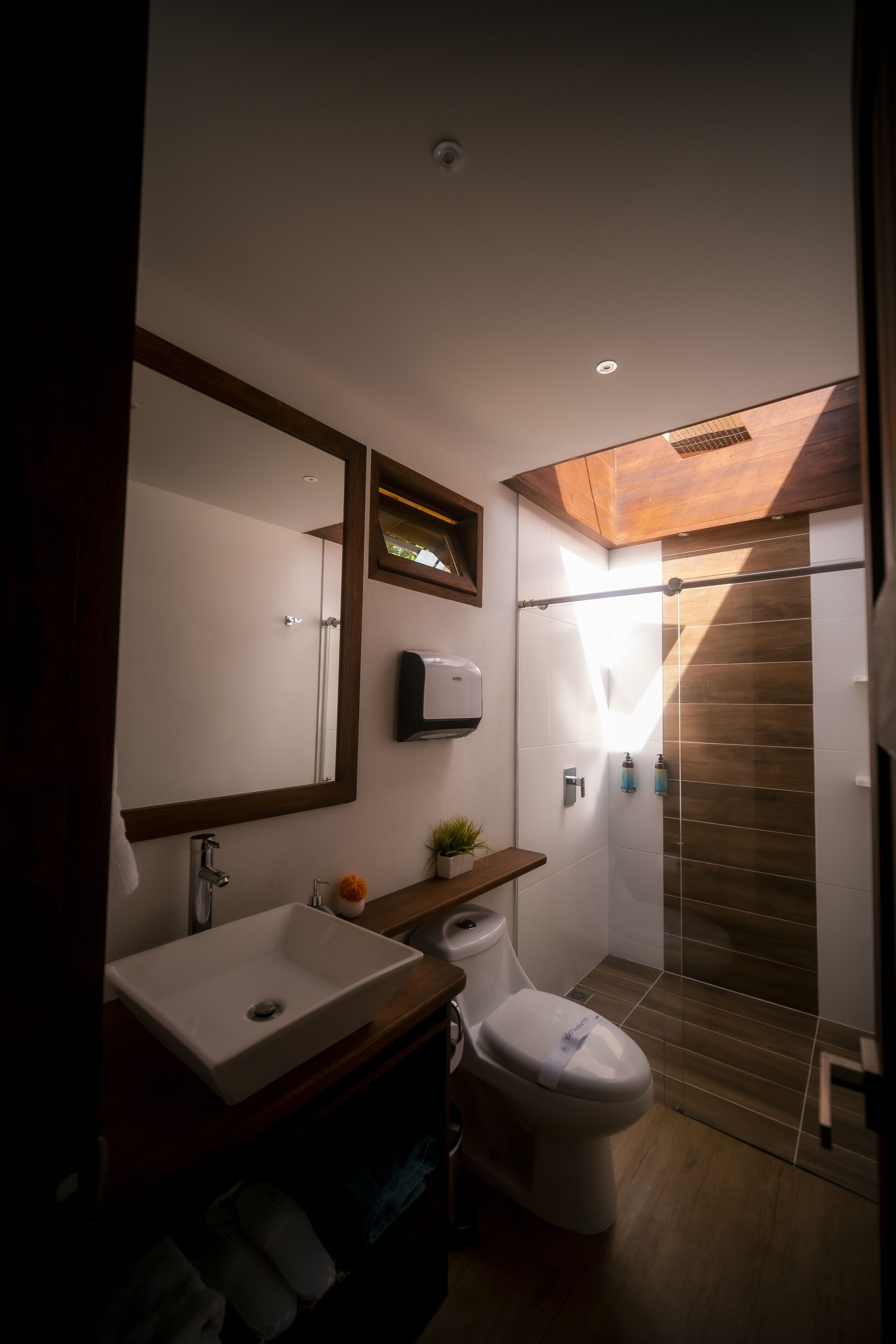 A modern bathroom with a large mirror, a sink, a toilet, and a shower.
