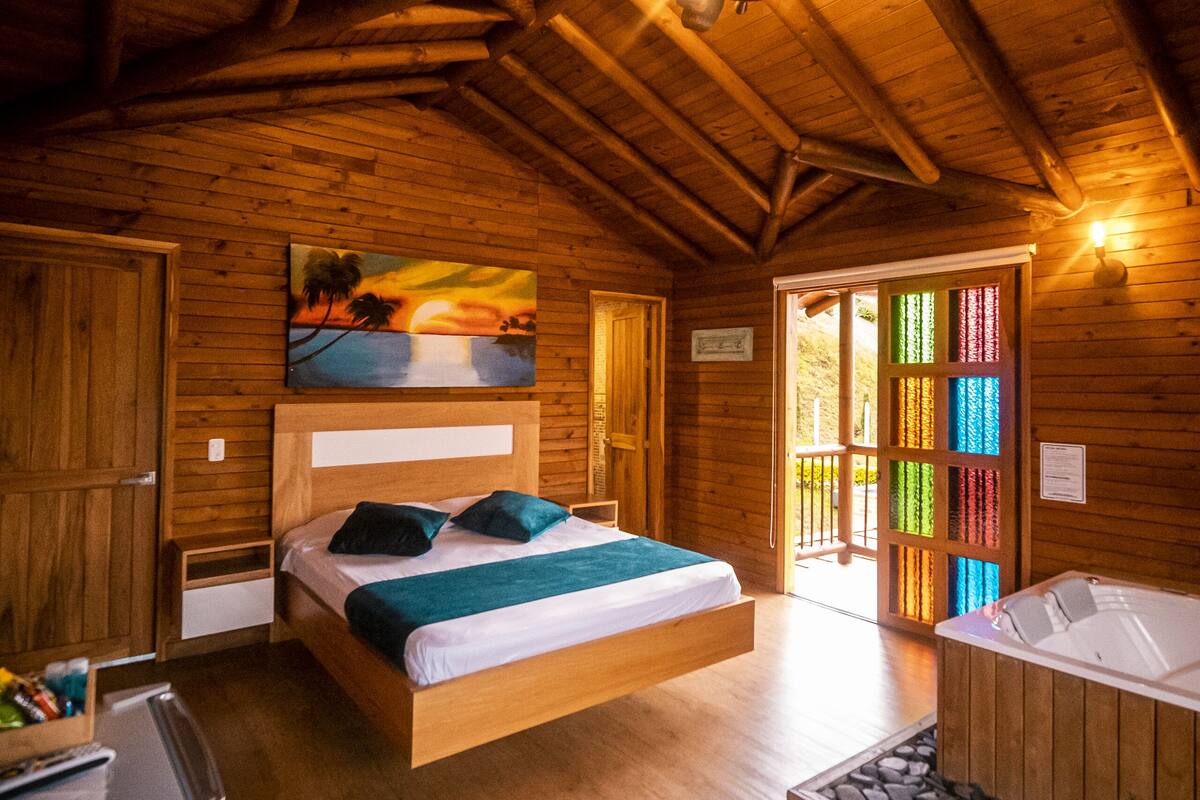 A wooden cabin with a bunk bed, a small kitchenette, a bathtub, and a colorful door.