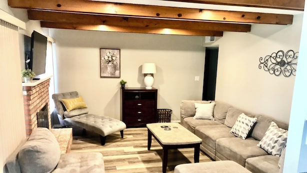 A living room with a fireplace, a sofa set, a coffee table, and a decorative wall piece. - Beautiful newly remodeled 3 bed 2 bath foothills home.  No cleaning fees. (Albuquerque)