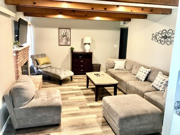 A living room with a fireplace, a sofa set, a coffee table, and a decorative wall piece.