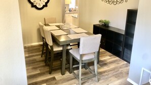 Un coin repas avec une table en bois, des chaises et une horloge murale.