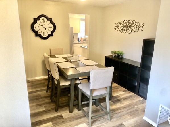 A dining area with a wooden table, chairs, and a wall clock.