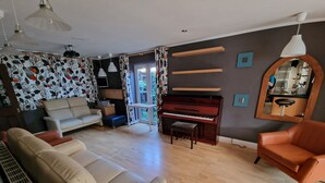A living room with a piano, sofa, and a chair.
