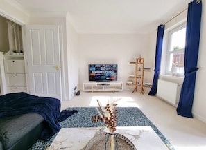 A modern bedroom with a bed, a TV, a bookshelf, and a window with curtains.