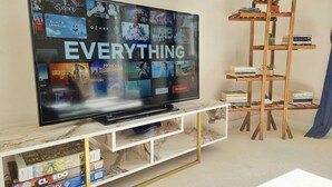 Un televisor de pantalla plana sobre un soporte de mármol y dorado, rodeado de libros y un estante de madera.
