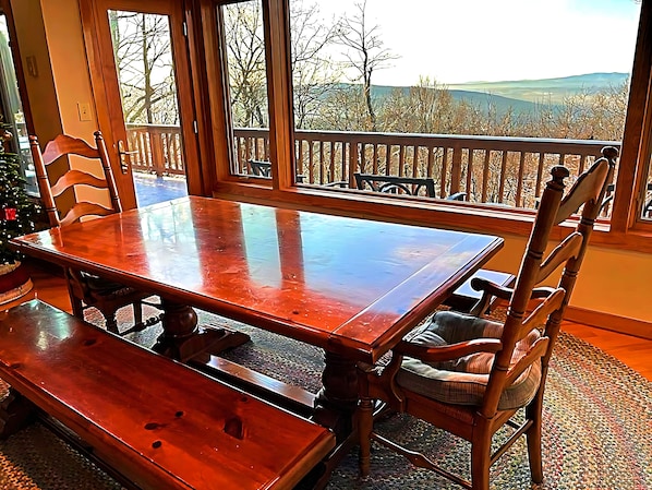 Enjoy meals with a view of the surrounding mountains from this room's dining area, featuring a table and chairs.