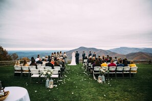 Couples can exchange vows amidst a serene mountain backdrop with a picturesque grassy ceremony area and elegant aisle decor.
