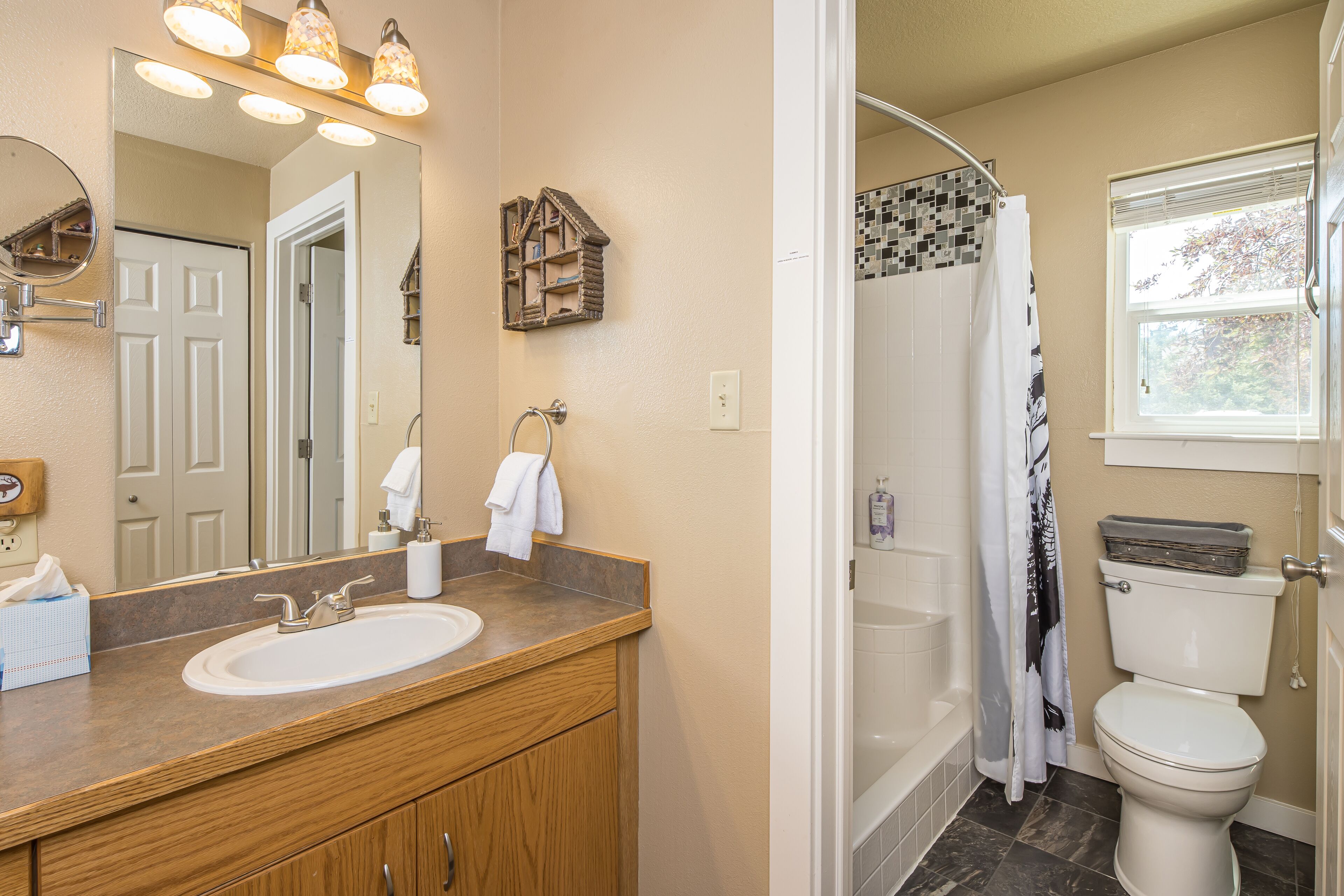 A bathroom with a wooden vanity, a large mirror, a toilet, and a shower.